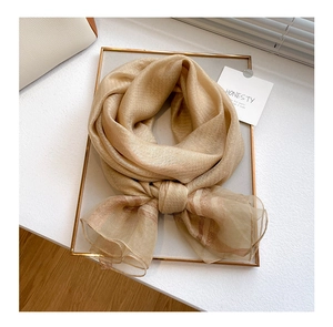 Detail of thin silk wool blend scarf in champagne gold on a stylish display tray