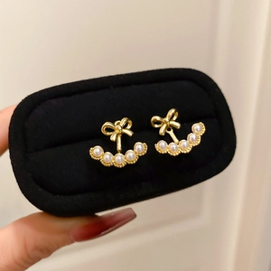 Macro detail of 18k gold plated bow earrings with pearls in a velvet jewelry box