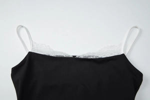 Détail d'un débardeur noir avec bordure en dentelle blanche et fines bretelles