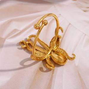 Detail of 18K gold-plated octopus ring on soft beige silk texture background