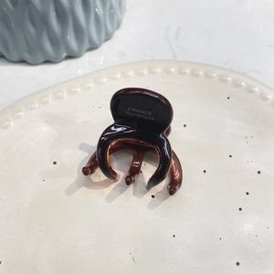 Close-up of amber acetate hair claw with France Handmade gold engraving on ceramic plate