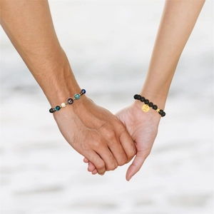 Close-up of couple wearing solar system beaded bracelets with zodiac metal charms