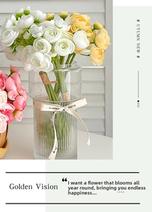 Close-up of artificial ranunculus in a striped glass vase with a decorative ribbon