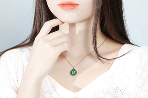 Detail of a gold malachite Taurus zodiac pendant necklace worn by a female model