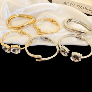 Close-up of minimalist gold and silver bangles with crystals on silk and velvet background