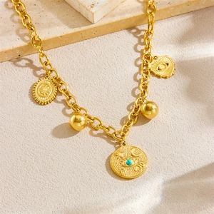 Vintage-Goldkette mit geprägten Augen- und Sonnenanhängern auf einer Steinplatte