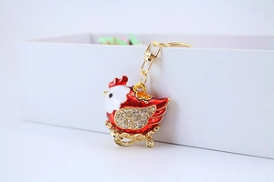 Detailed close-up of a red enamel chicken keychain with crystals and gold lobster clasp