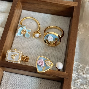 Detailed macro view of four vintage baroque pearl rings with blue enamel flower designs