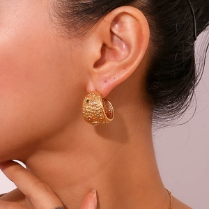 Detail of chunky gold hoop earrings featuring multicolor zircon stones and hammered texture