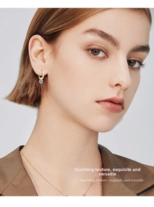 Close-up of gold drop earrings with moissanite stones and matching necklace on a model