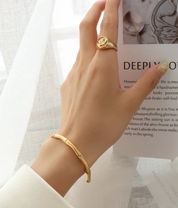 Detail of 18K gold bamboo style bangle and vintage character relief signet ring
