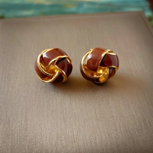 Macro view of vintage gold-tone love knot stud earrings with dark enamel filling