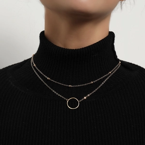 Detail of gold double-layer necklace with beads and ring pendant on a black sweater