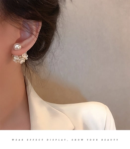 Detailed view of pearl flower stud earrings worn on ear with soft lighting effect