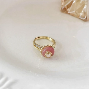 Vista dettagliata dell'anello dorato con pietra rosa, piccola perla e micro diamanti
