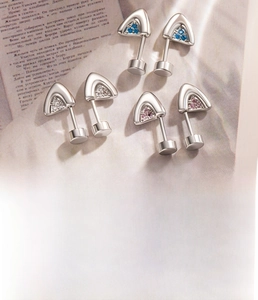 Macro detail of cat-ear titanium steel cartilage studs with colorful zircon stones