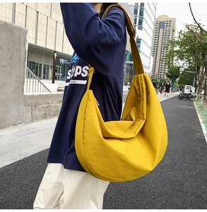 Detail view of a bright yellow large capacity oxford cloth half-moon crossbody bag in use