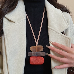 Detail of geometric acrylic pendant with marble texture on long sweater necklace