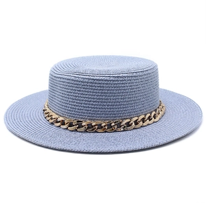 Detail view of a blue straw flat top hat featuring a chunky gold chain and woven texture