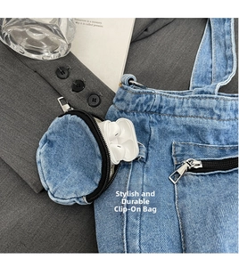 Close-up of a mini denim coin pouch with metal clip holding wireless earbuds