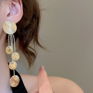 Detailed close-up of golden fringe earrings featuring five textured geometric metal disks