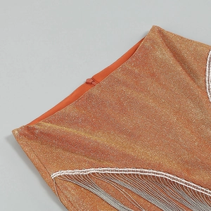 Detailed close-up of orange metallic knit fabric with silver wavy fringe and hidden zipper