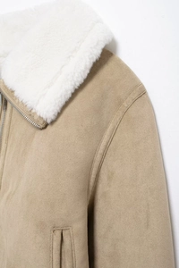 Détail de la veste en daim kaki avec col en fourrure blanche et fermeture éclair en métal