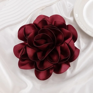 Detailed close-up of dark wine red satin rose brooch with layered silk petals