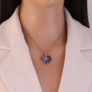 Detail of a gold bead chain necklace with a purple heart gemstone and star pendant