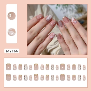 French champagne cat-eye press-on nails with white petals, pearls, and black dots