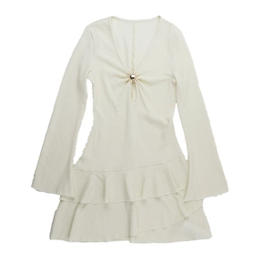 Détail de robe courte crème gaufrée avec ourlet à volants et boucle soleil en métal
