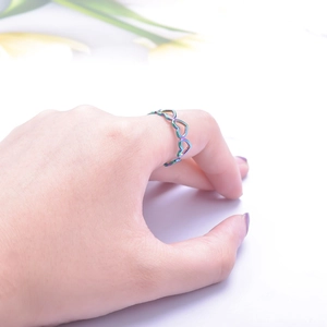 Close-up of rainbow gradient heart-shaped hollow ring on finger with white background
