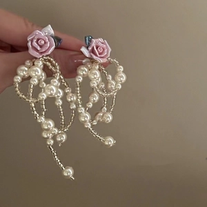 Detail of pink rose and layered pearl tassel earrings with delicate golden beads