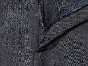 Detail shot of heavy-duty metal zipper on charcoal grey twill wool trousers fabric