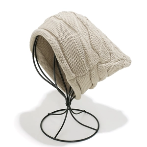 Close-up of cable knit texture and cuff detail on a beige winter beanie hat