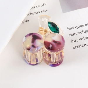 Elegant purple marble acetate hair claw with green rhinestone on a book background