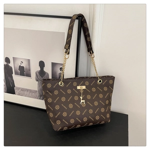 Close-up of vintage monogram tote bag with gold chain strap and deer charm detail