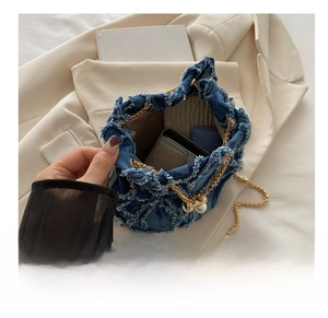 Macro view of the blue denim bucket bag interior showing large capacity and pearl clasp
