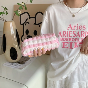 Close-up of pink and white quilted pencil case held by hand in a soft studio setting