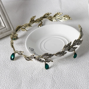 Detailed view of vintage gold leaf tiara with emerald green water drop pendants