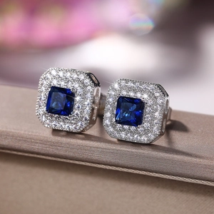 Close-up of square princess cut blue sapphire halo stud earrings with silver setting