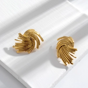 Elegant gold wheat ear stud earrings with twisted metal texture on a stone surface