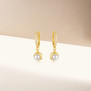 Detail of gold pearl earrings with shimmering zircon accents and elegant metal finish
