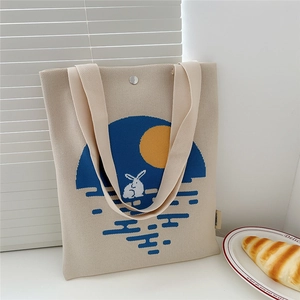 Detail of knit tote bag with rabbit and moon patterns and snap closure button
