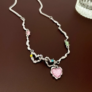 Détail du collier coeur en argent avec pierres précieuses sur surface en cuir sombre