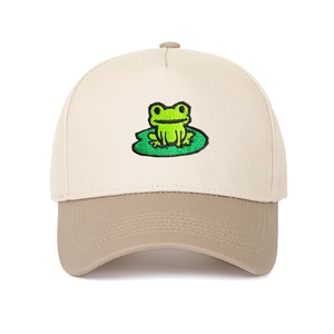 Close-up of a two-tone baseball cap featuring detailed frog and lotus leaf embroidery