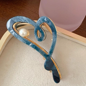 Macro shot of marble-textured acetate heart hair claw with pearl and gold metal trim