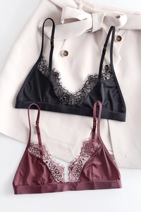 Dettaglio di bralette in pizzo nero e bordeaux con bordo ciglia su tessuto di seta