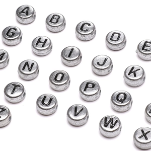 Detailed view of silver acrylic alphabet beads in a flat round shape for DIY jewelry making