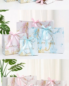 Detail of marble pattern gift bags with gold foil text and ribbon handles in various sizes